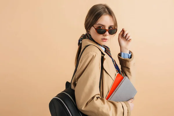 Young beautiful girl in trench coat and sunglasses with backpack — Stock Photo, Image