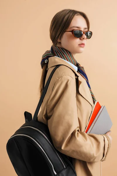 Jovem bela senhora em casaco de trincheira e óculos de sol com mochila — Fotografia de Stock