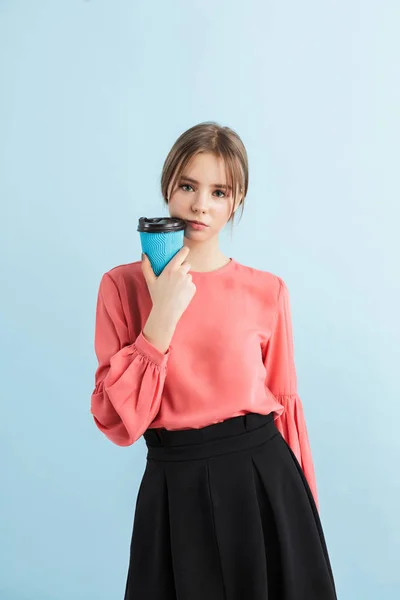 Joven chica bonita en blusa y falda sosteniendo taza de café a g —  Fotos de Stock