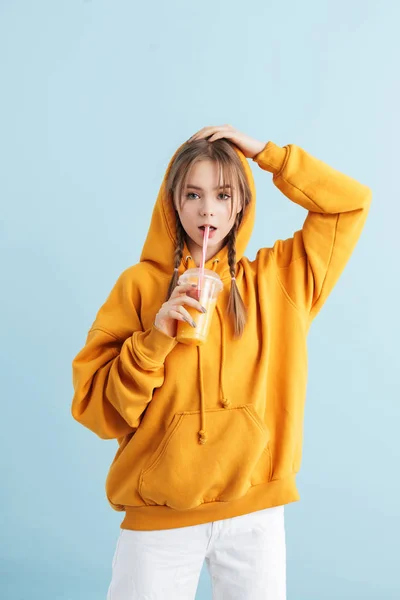 Jong mooi meisje met twee vlechten in oranje hoodie drinken j — Stockfoto