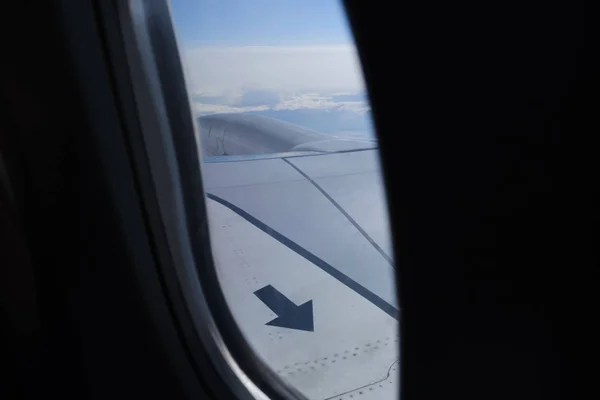 Pfeilschild auf dem Flugzeugflügel in den Himmel Bullauge Ansicht — Stockfoto