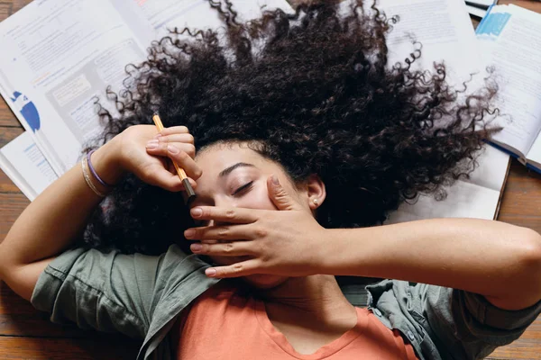 Siswa muda yang lelah dengan rambut keriting gelap tergeletak di lantai dengan buku teks di sekitar bermimpi menguap di rumah — Stok Foto