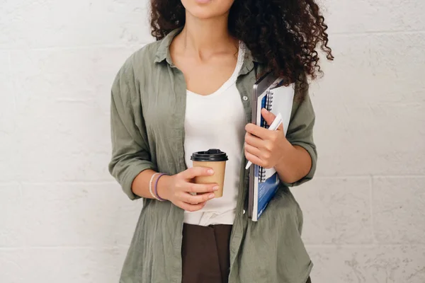 特写照片的学生女孩黑卷发在卡其衬衫拿着笔记本电脑与记事本和咖啡去手 — 图库照片