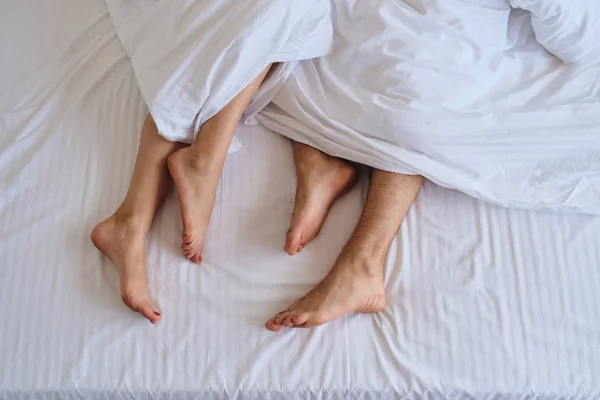 Close up photo of man and woman legs in white bed at cozy home — Stock Photo, Image
