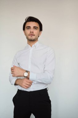 Beyaz gömlek li ve siyah pantolonlu genç yakışıklı esmer adam hayalperest beyaz arka plan üzerinde bir kenara bakarak izlemek