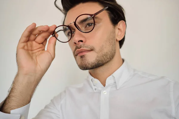 Portré fiatal csinos barna férfi fehér inget és szemüvegek álmodva néz félre mint a fehér háttér — Stock Fotó