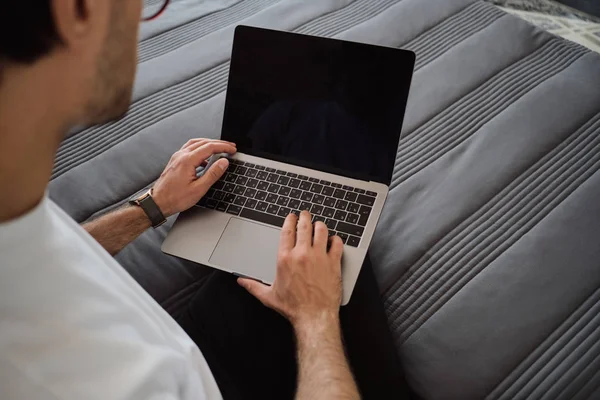 Feche a foto do homem sentado na cama trabalhando no laptop moderno em casa — Fotografia de Stock