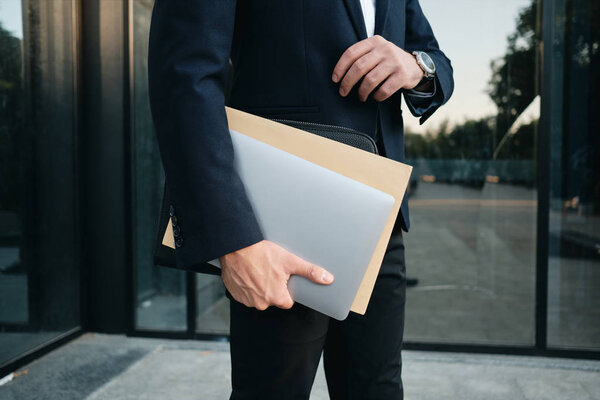 Close up man in classic black suit standing outdoor alone holdin