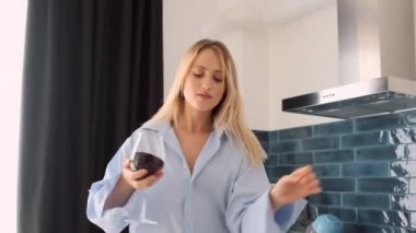 Erkek gömlek güzel rüya gibi sarışın kadın mutlu evde mutfakta şarap kadehi ile dans çekim izleme