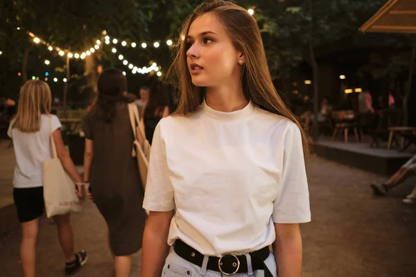 Fiatal gyönyörű nő, fehér póló álmodosan látszó kívül álló városi parkban éjjel — Stock Fotó