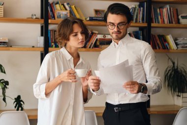 Genç çekici iş arkadaşları düşünceli modern ofiste birlikte yeni proje tartışıyor kağıtları ile ayakta