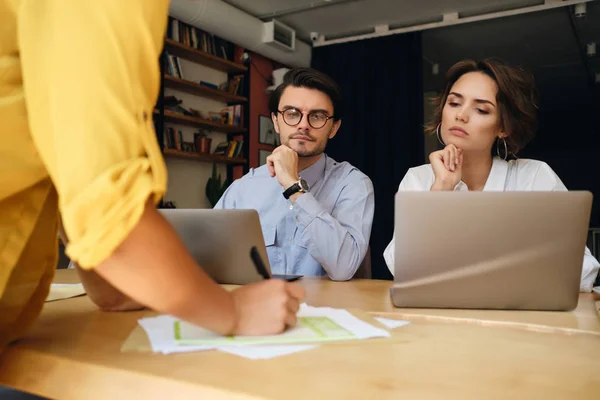 Grupo de colegas de negocios sentados en el escritorio con computadora portátil que trabaja cuidadosamente con papeles en la oficina moderna — Foto de Stock