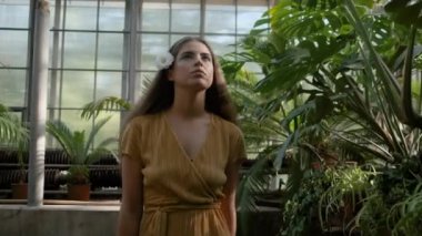 Saç hayali güzel tropikal sera etrafında yürüyüş çiçek ile romantik elbiseli genç çekici kadın Orta çekim 