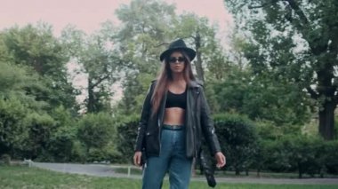 Deri ceket ve şapka güneş gözlüğü takan güzel kız çekim etrafında Izleme rüya gibi eski bahçede yürürken