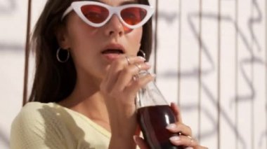 Mayo içen soda güzel esmer kız çekim izleme düşünceli plajda ahşap arka plan üzerinde kamera bakarak 