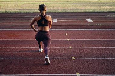 Spor giyimli sportif kızın şehir stadyumunda esneme egzersizleri yaptığı nasiçli kızın arka görünümü. Fitness kadın açık egzersiz ısınma yapıyor
