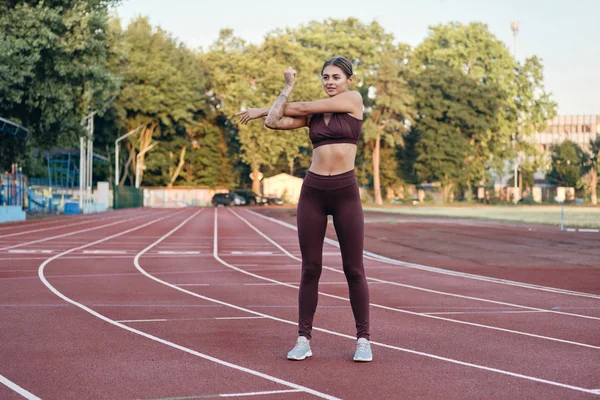 Bella atleta ragazza in abbigliamento sportivo facendo allenamento di stretching della mano sullo stadio della città — Foto Stock