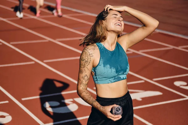 Menina atleta molhado alegre em sportswear feliz descansando depois de correr no estádio da cidade — Fotografia de Stock