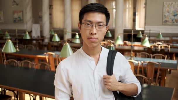 Üniversite Kütüphanesinde Kameraya Neşeyle Bakan Genç Gülümseyen Asyalı Erkek Öğrenciportresi — Stok video