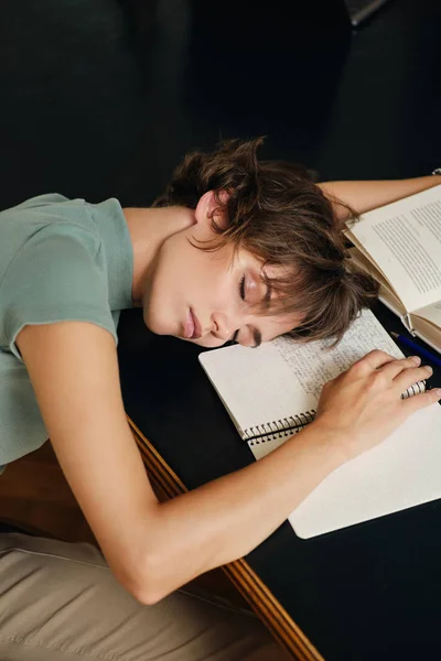 Üniversite kütüphanesinde eğitim sırasında kitap ve özet ile masa başında uyuyan genç yorgun kız öğrenci portresi — Stok fotoğraf