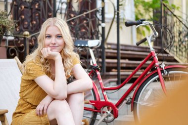 Elbise güzel romantik sarışın kız hayalrüya şehir caddesinde klasik bisiklet ile dinleniyor kamera bakıyor