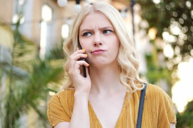 Üzgün sarışın kız Portresi sinir bozucu uzakta cep telefonu açık konuşma bakıyor