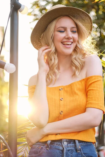 Portrait of cheerful blond girl in hat joyfully laughing standing on city street — Stock Photo, Image