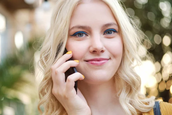 Close up beautiful smile blond girl dreamily looking in camera talking on cellphone outdoor — Stok Foto