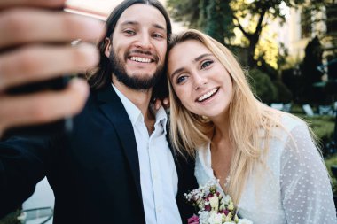 Genç çekici gülümseyen damat ve gelin sevinçle birlikte açık havada selfie alarak