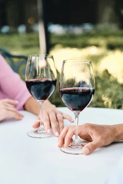 De cerca foto de la pareja con copas de vino tinto en la cita romántica en el restaurante al aire libre — Foto de Stock