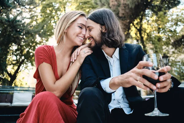 Joven hermosa pareja sensual con copa de vino tinto felizmente hablando en la fecha en el restaurante al aire libre — Foto de Stock