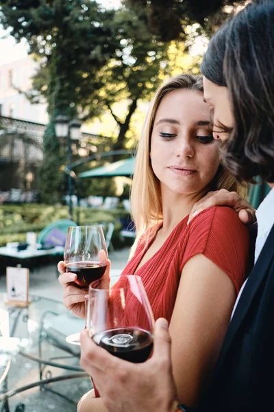 Joven pareja sensual atractiva con copas de vino tinto en la fecha en el hermoso restaurante al aire libre — Foto de Stock