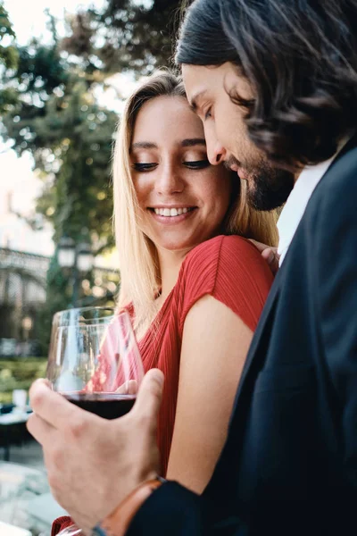 Joven pareja romántica feliz con copas de vino tinto descansando en la fecha en el hermoso restaurante al aire libre — Foto de Stock