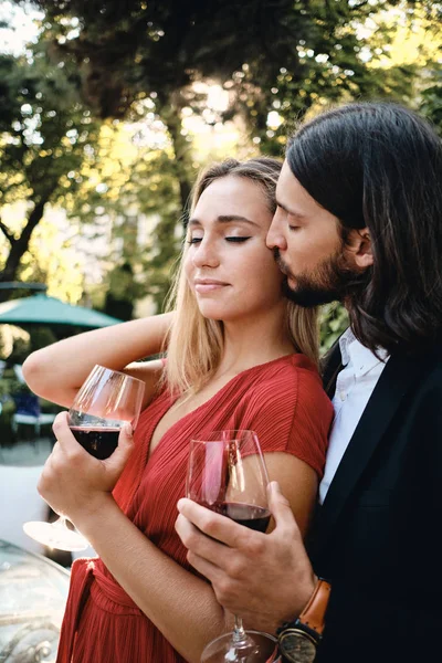 Joven pareja romántica sensual con copas de vino tinto en la fecha en el restaurante al aire libre — Foto de Stock