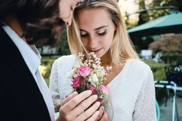 Close-up jonge romantische bruidegom en prachtige bruid sensueel houden boeket van bloemen buiten — Stockfoto