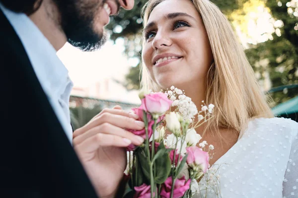 Mutlu damat açık bakarak çiçek buketi ile çekici şehvetli sarışın gelin kadar yakın — Stok fotoğraf