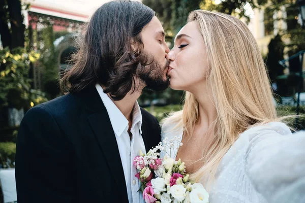 Jovem belo noivo e noiva sensualmente beijando tirar selfie no jardim do restaurante — Fotografia de Stock