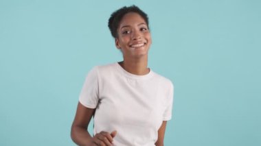 Mavi arka planda dans eden neşeli Afro-Amerikalı kız portresi