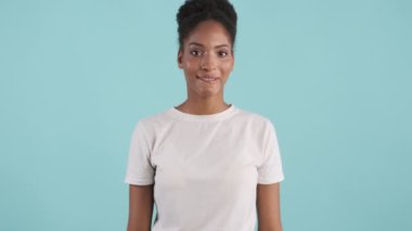 Güzel bir Afro-Amerikalı kızın mavi arka planda büyüleyici bir şekilde flört edişinin portresi