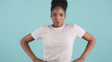 Kızgın Afrikalı Amerikalı bir kızın portresi suç işleyerek mavi arka planda kameraya bakıyor.