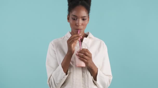 非洲裔美国女孩在蓝色背景下喝着无味奶昔的形象 — 图库视频影像