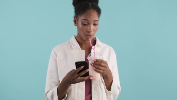 Atractiva Chica Afroamericana Sonriente Felizmente Usando Teléfono Celular Bebiendo Batido — Vídeos de Stock