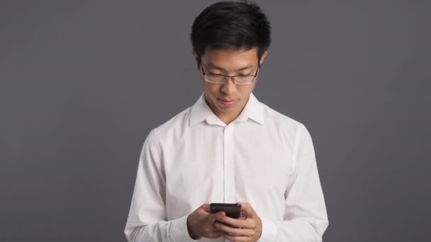 Joven Sonriente Asiático Hombre Gafas Felizmente Utilizando Teléfono Celular Sobre — Vídeo de stock