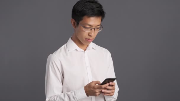 Joven Sorprendido Asiático Hombre Gafas Usando Teléfono Celular Wow Expresión — Vídeos de Stock