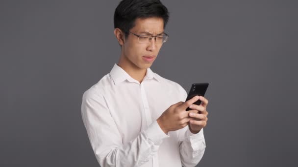 Molesto Hombre Asiático Gafas Emocionalmente Usando Teléfono Celular Expresión Frustrante — Vídeo de stock