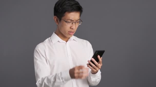 Ung Upprörd Asiatisk Man Glasögon Besvikna Med Mobiltelefon Förlora Uttryck — Stockvideo