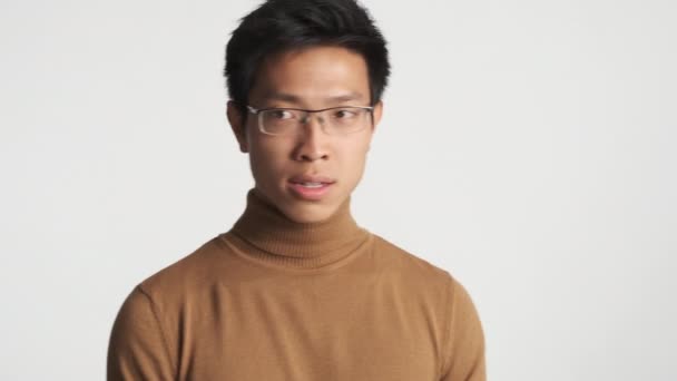 年轻的 时髦的 头戴眼镜的 对白色背景感到困惑的亚洲男人 发生什么事了 — 图库视频影像