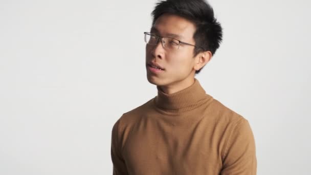 年轻恼怒的戴眼镜的亚洲人怒气冲冲地环视周围的白色背景 — 图库视频影像