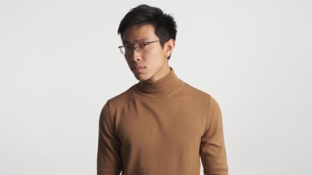 眼鏡の中の若い真面目なアジア系の男は 何のジェスチャーも見せずに孤立したままにしてしまう 表現に関わらず — ストック動画
