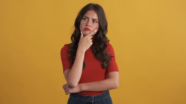 Kırmızı Tişörtlü Güzel Dalgın Esmer Kız Sarı Arka Plana Dikkatlice — Stok video